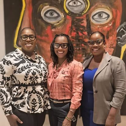 Three CIWiL AB women smiling in front of artwork.